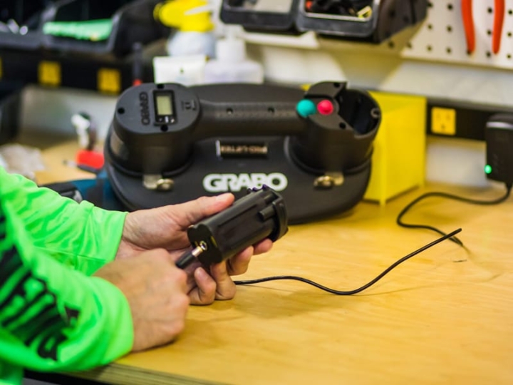 GRABO batteri med stikket fra en GRABO oplader i et værksted